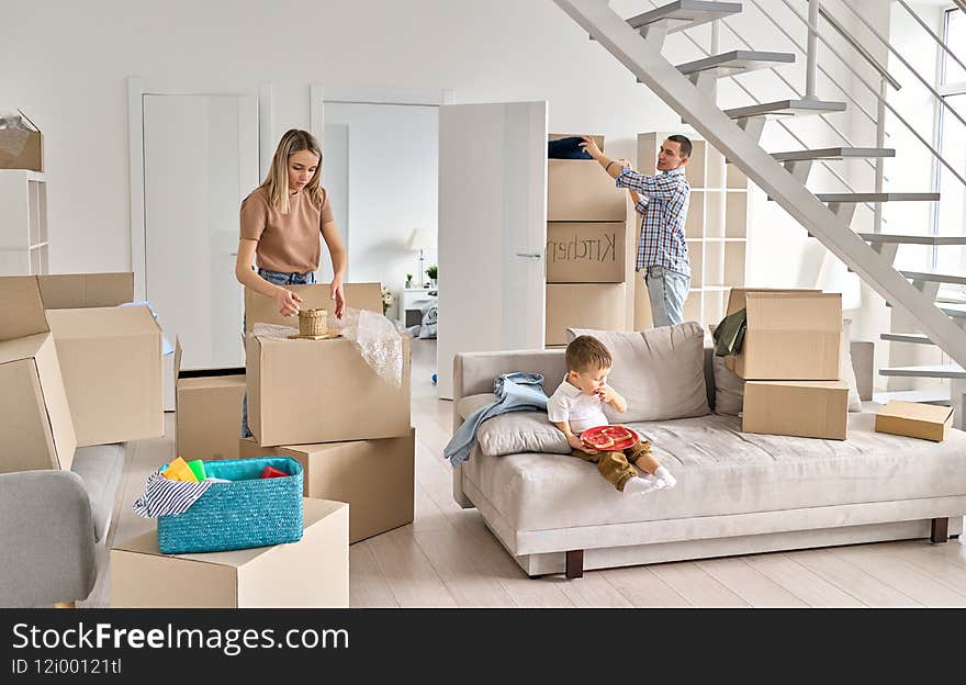 Young Couple With Kid At Home Unpacking Boxes After Relocating.