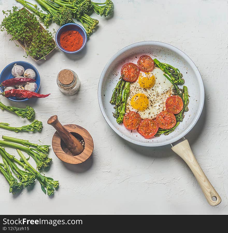 Fried Eggs With Tomatoes And Broccoli In White Frying Pan On Kitchen Table With Ingredients. Top View. Healthy Breakfast