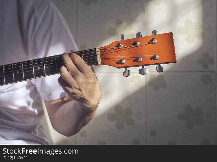Sunlight and shadow on surface of teenage boy hand practicing to play the guitar at home. Sunlight and shadow on surface of teenage boy hand practicing to play the guitar at home