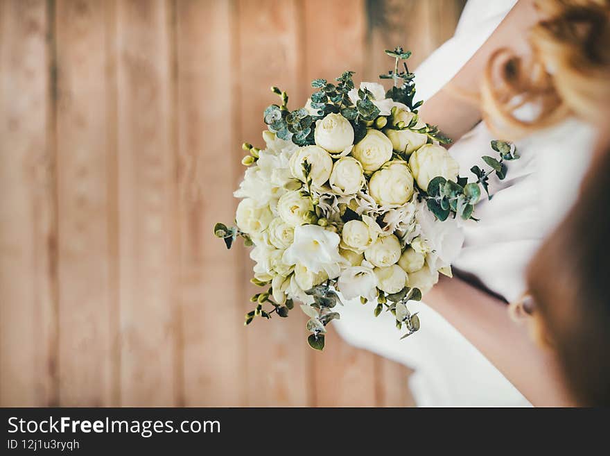 Horizontal photo close-up of a girl holding a wedding bouquet of peonies in her hands. Top view