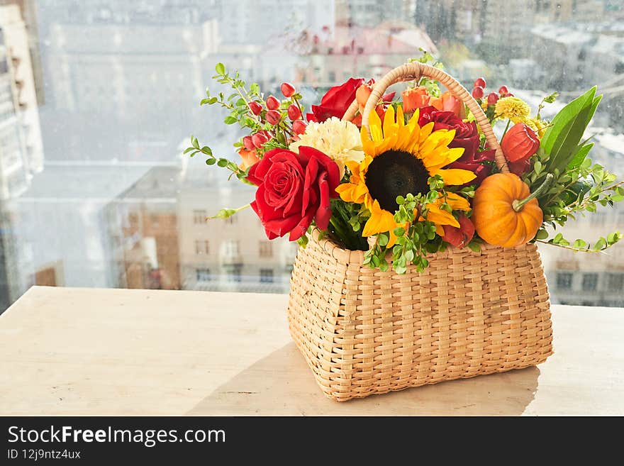 Mixed autumn flowers in basket, bouquet is on the windowsill with copy space.