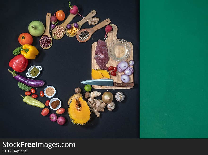 Fresh meats, vegetables and spices are laid out on a black table