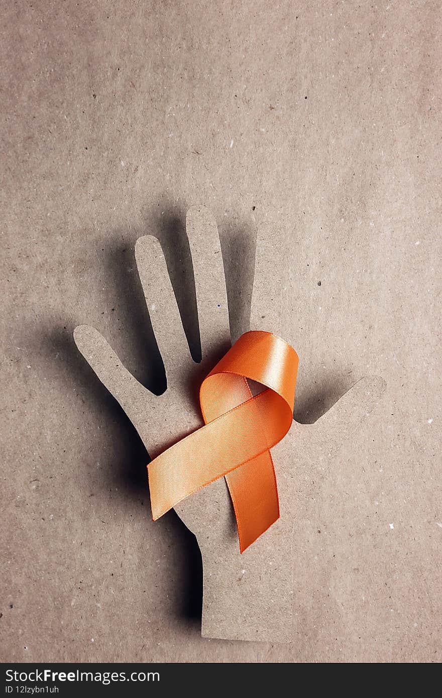 World Multiple Sclerosis Day. Orange awareness ribbon and hand silhouette on a brown background