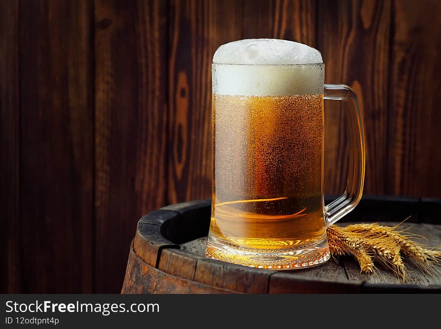 mug of beer with wheat ears on barrel as table. mug of beer with wheat ears on barrel as table