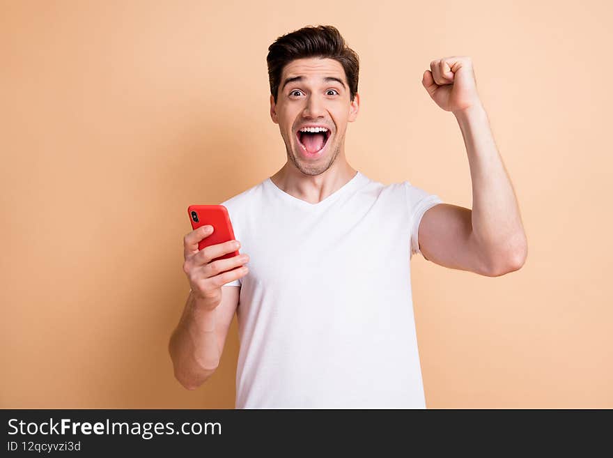Photo of astonished person fist up open mouth shout yes celebrate triumph isolated on beige color background.