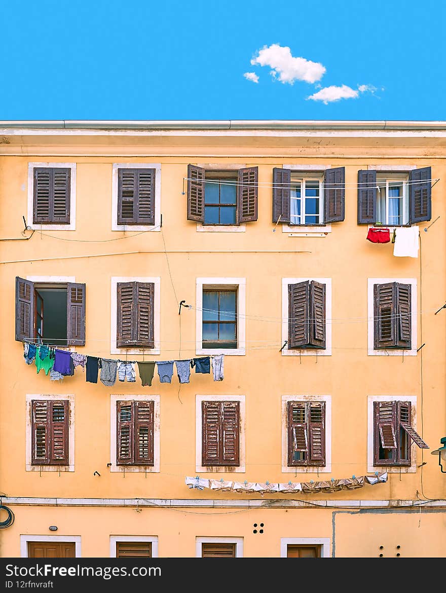 Picturesque typical Italian slum residential house under a blue summer sky with a single cloud in Italy. Wall with many