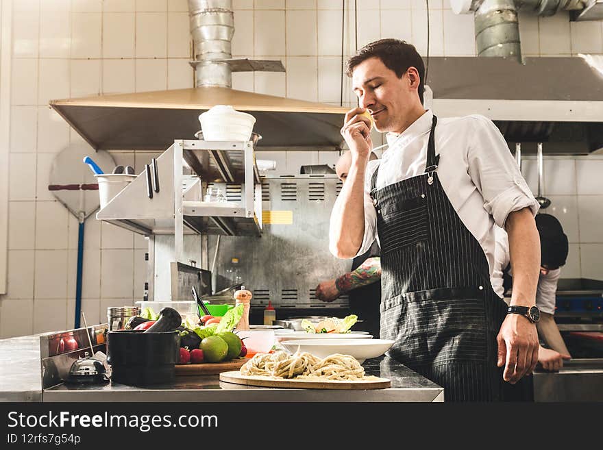 Professional chef cooking in the kitchen restaurant at the hotel, preparing dinner. A cook in an apron makes a salad of