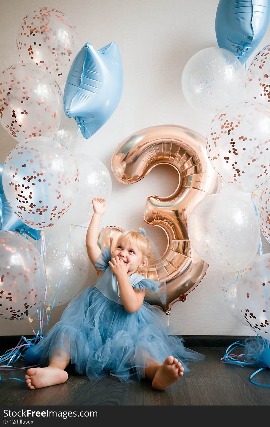 Birthday of a little blonde girl. Child in festive balloons. High quality photo