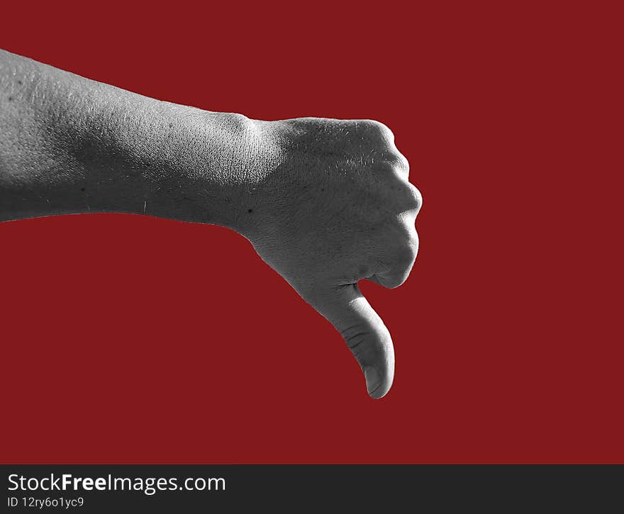 Black and white photography of male hand showing thumb down gesture isolated on dark red  background