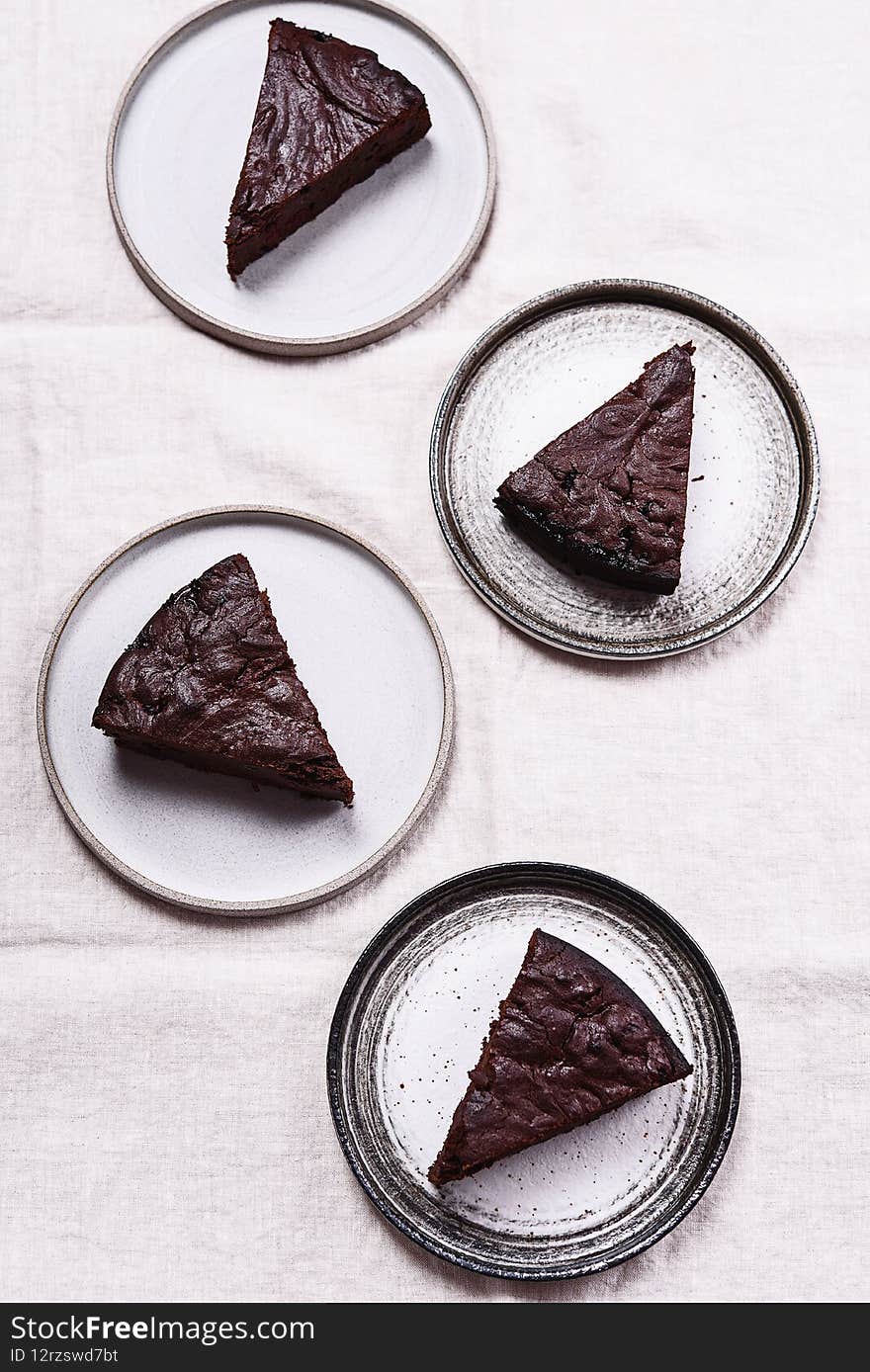 Slices of rich moist chocolate cherry cake. Homemade dark chocolate sweet brownies cakes on greige linen tablecloth. Selective focus