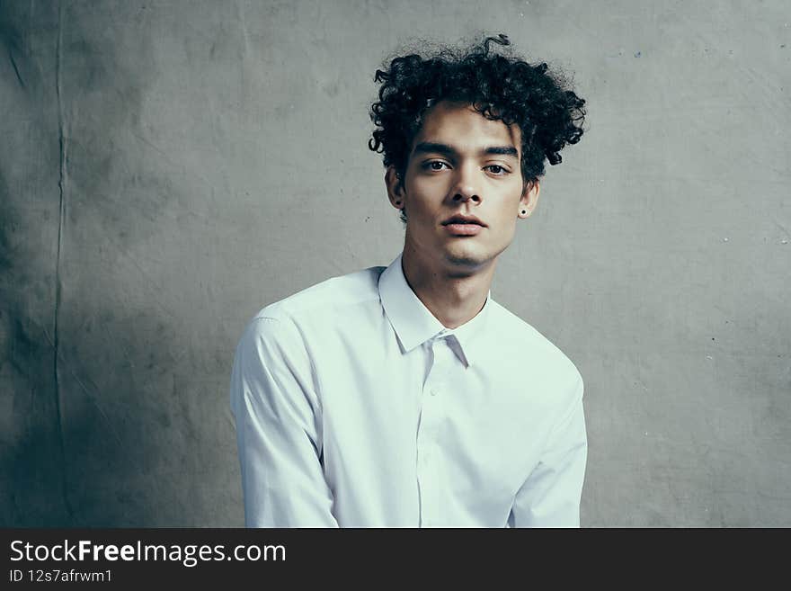 man in white shirt curly hair emotions studio modern style. High quality photo