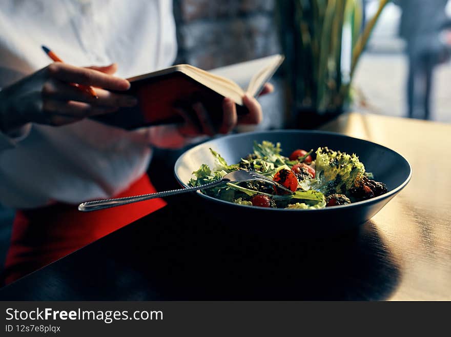 notepad with a pen in hand and salad in a plate restaurant cafe inscription
