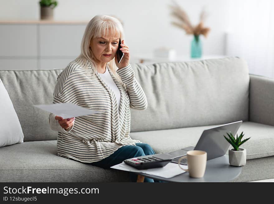 Lady holding paper reading report talking on phone at home