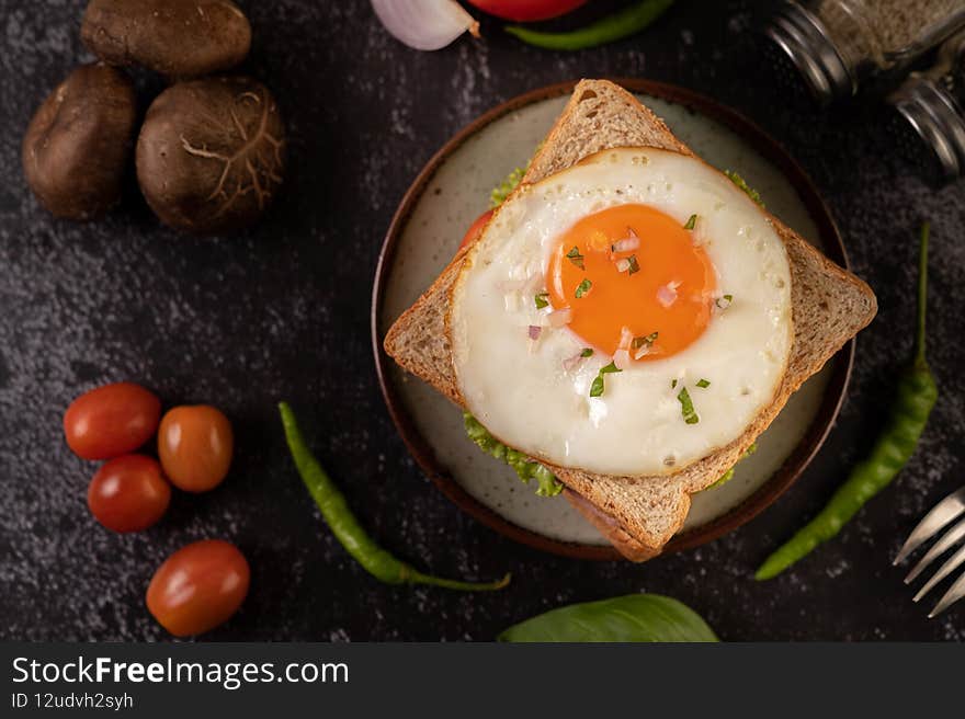 Breakfast sandwich made with bread, fried egg, ham, and lettuce