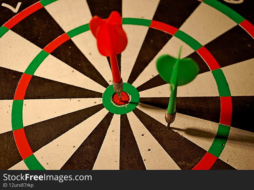 Color photography of darts with dartboard, Darts or dart-throwing is a competitive sport in which two or more players bare-handedly throw small sharp pointed missiles known as darts at a round target known as a dartboard