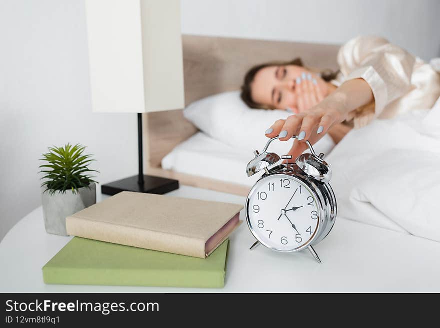 Blurred Woman Holding Alarm Clock Near
