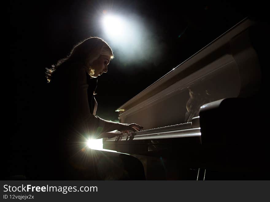Close up view of a girl plays piano in the concert hall at scene