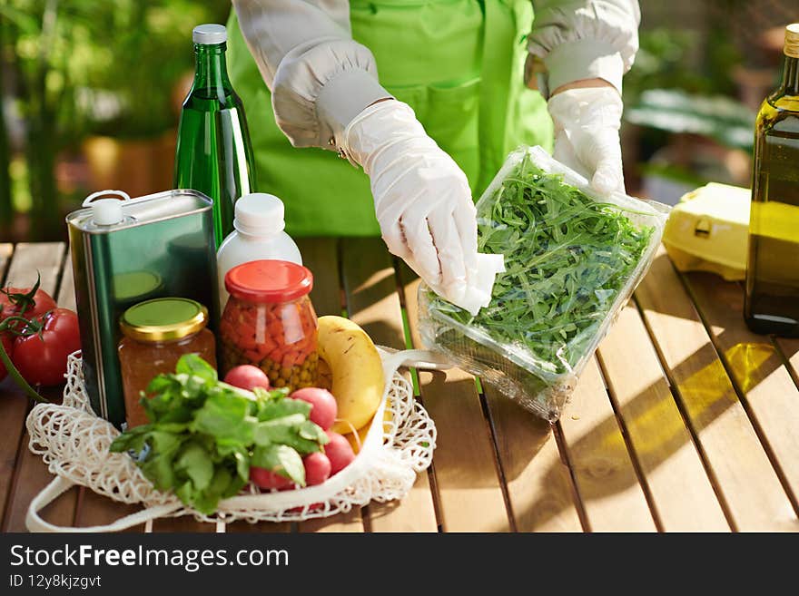 Closeup on housewife in green apron in modern kitchen disinfecting groceries after supermarket. Closeup on housewife in green apron in modern kitchen disinfecting groceries after supermarket