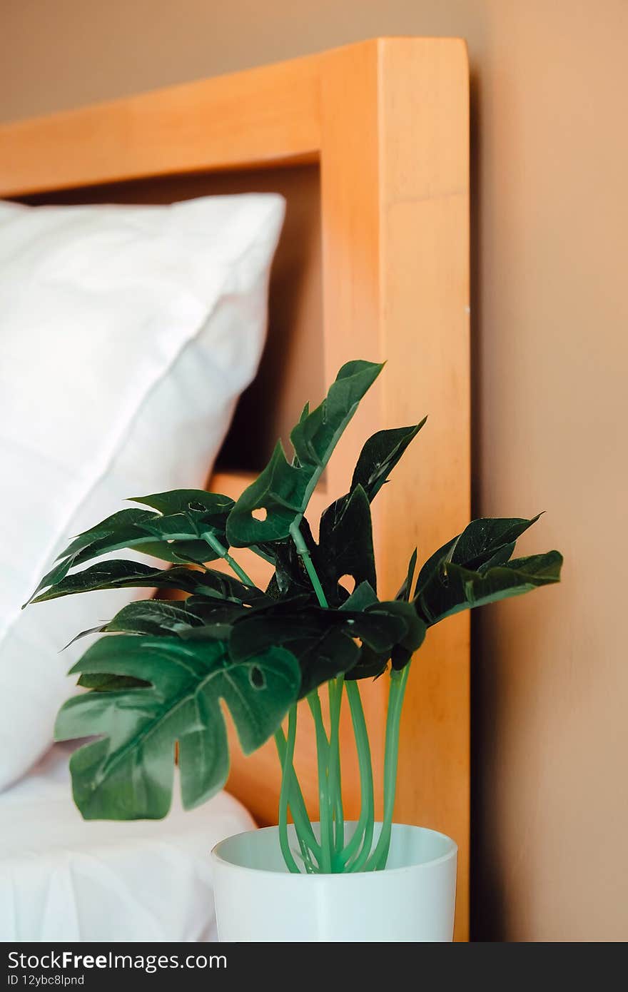 Artificial plant decoration in bedroom. Modern white bed and pillow in the morning mood