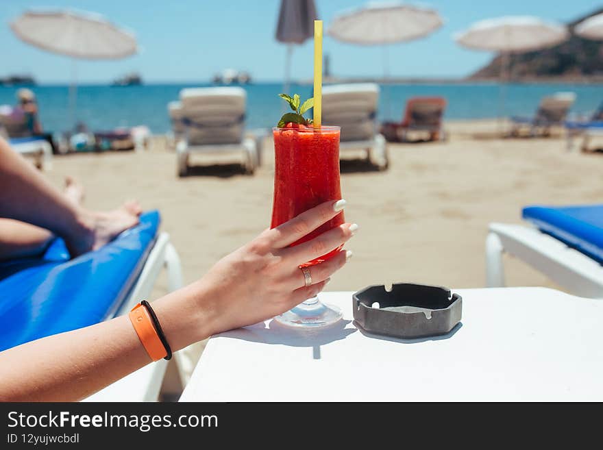 a woman lies on a lounger and looks at the sea and in her hands a cocktail