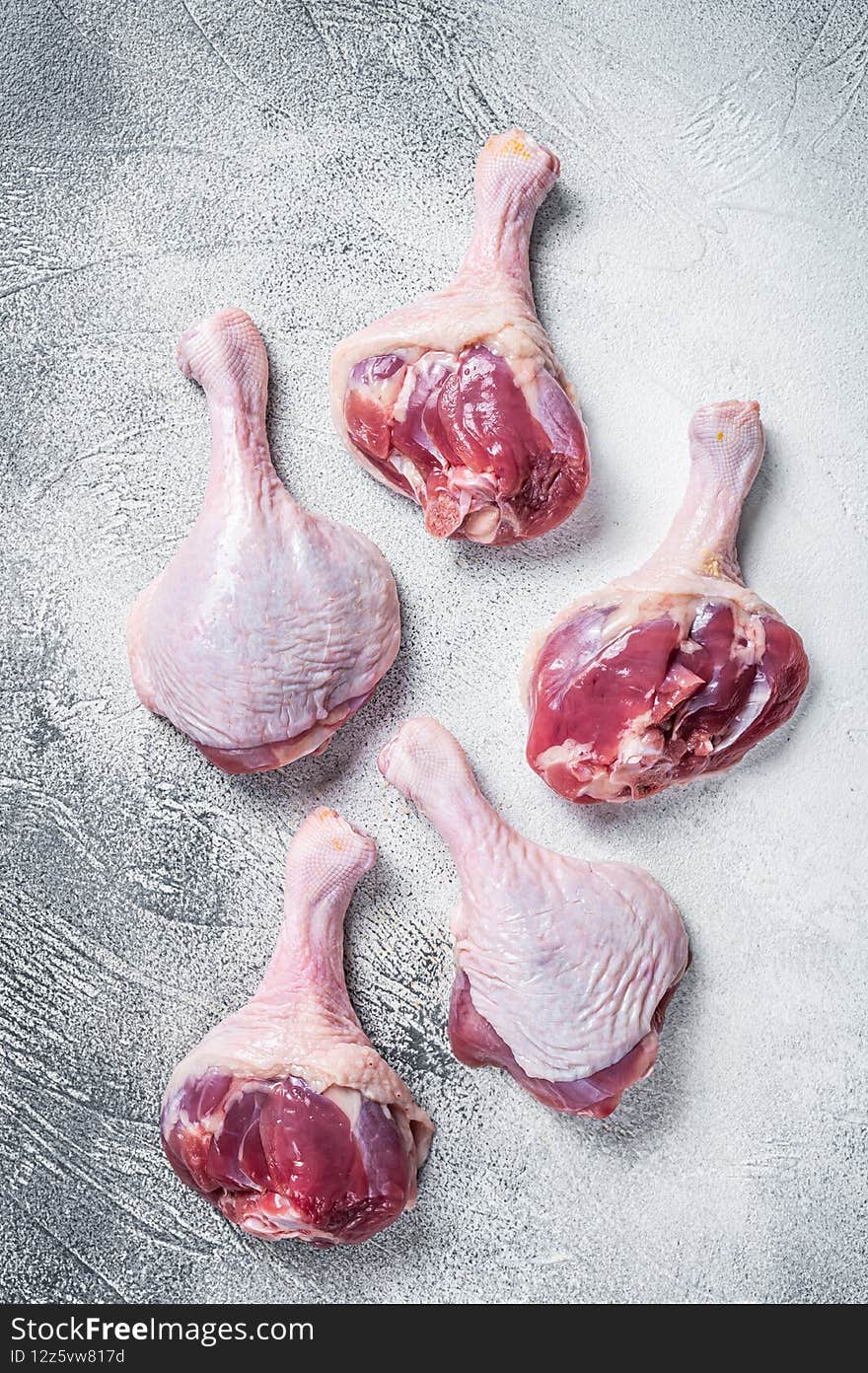 Raw Duck legs drumsticks on butcher table. White background. Top view