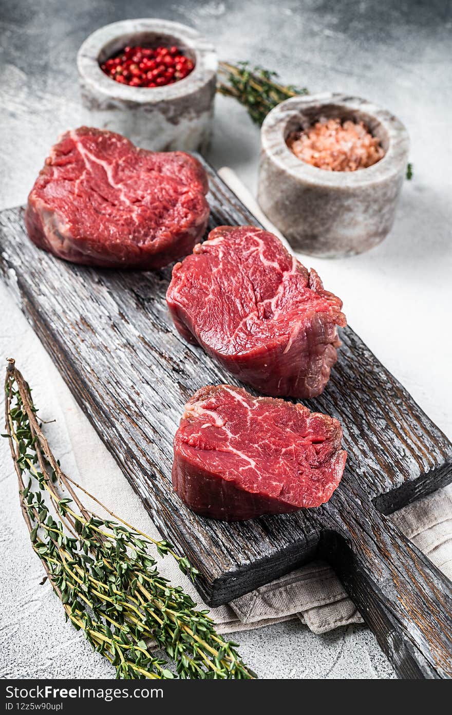 Fillet mignon beef raw steaks on a wooden board with salt and pepper. White background. Top view.