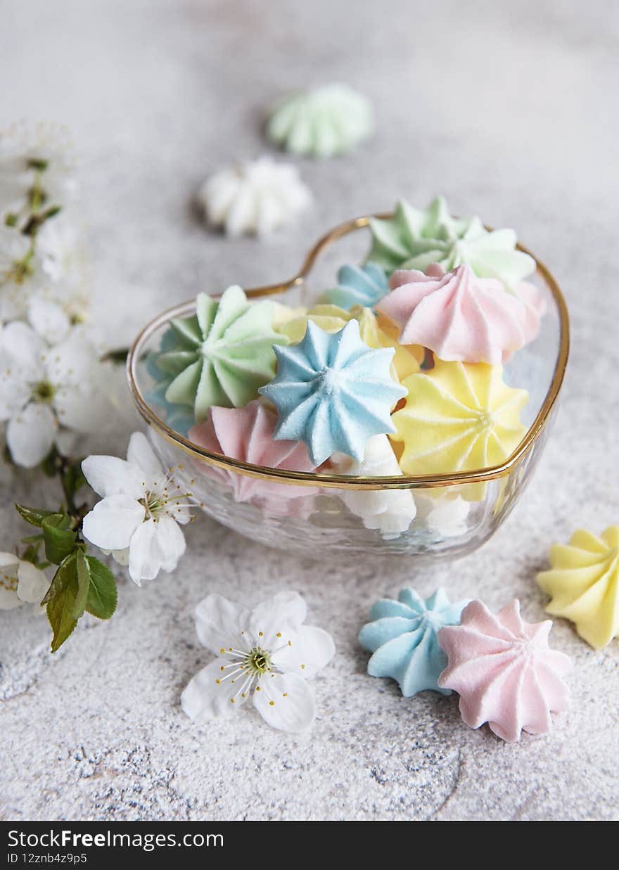 Small colorful meringues in the  heart shaped bowl on concrete background