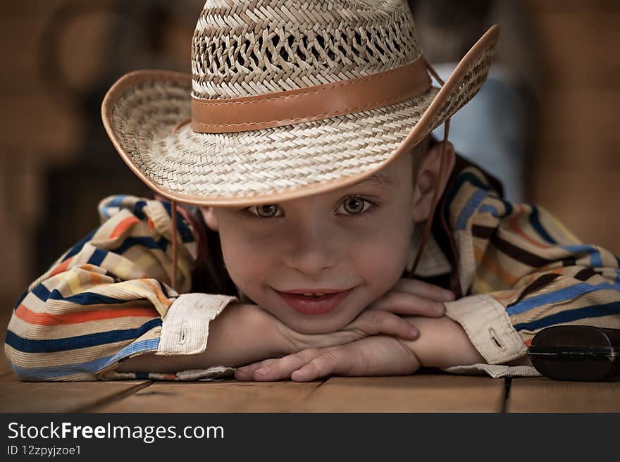 Happy child smiles. A portrait of a kid in a cowboy costume rejoices and dreams of adventure  in the Wild West