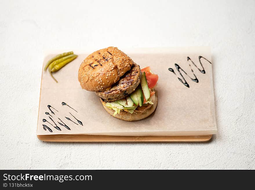 Burger ingredients, Sesame grilled Bun with fried meat, fresh cucumber and tomato served on parchment paper. Tasty snack. Horizontal format. Hamburger composition on white background.