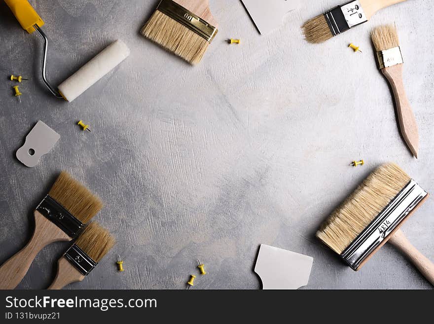 Spatulas for application of putty and brushes and rollers for painting on a gray concrete background.Top view