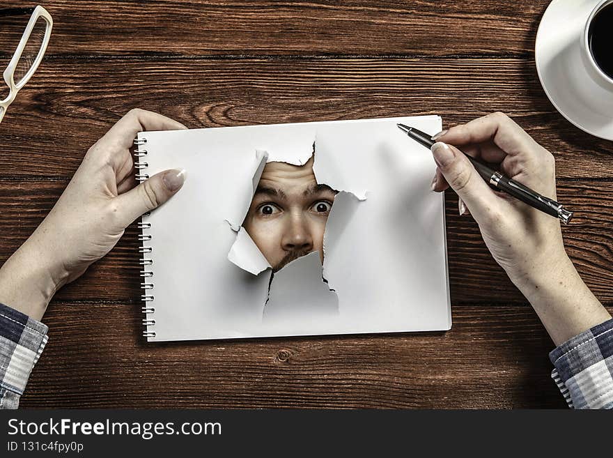 Male face through the hole in paper. Mixed media