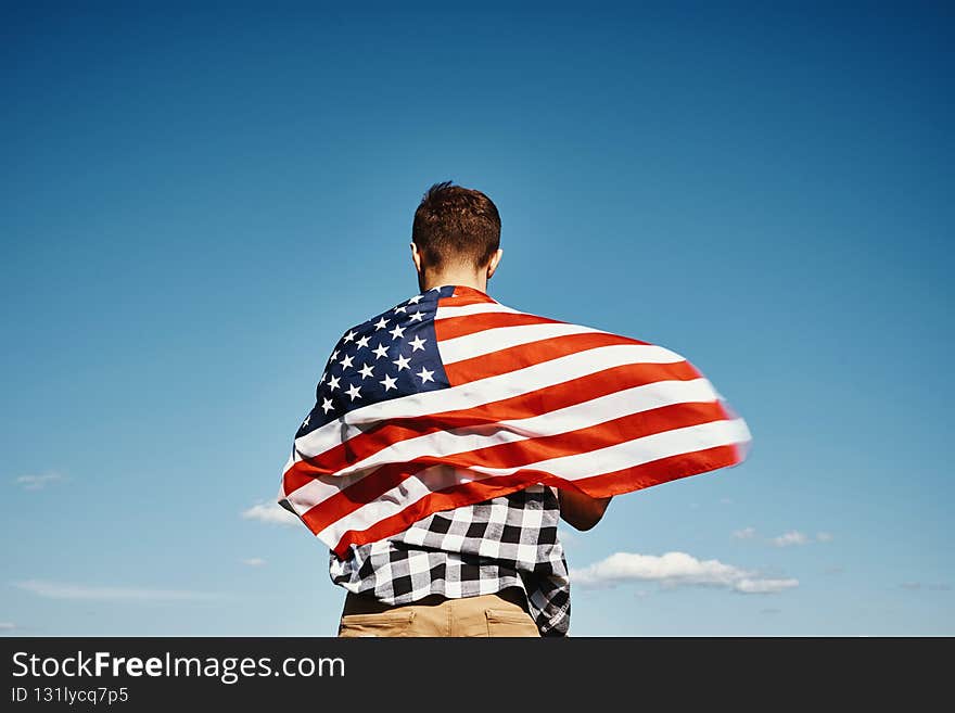 American flag outdoors. Man holds usa national flag against blue cloudy sky. 4th July Independence Day. American flag outdoors. Man holds usa national flag against blue cloudy sky. 4th July Independence Day
