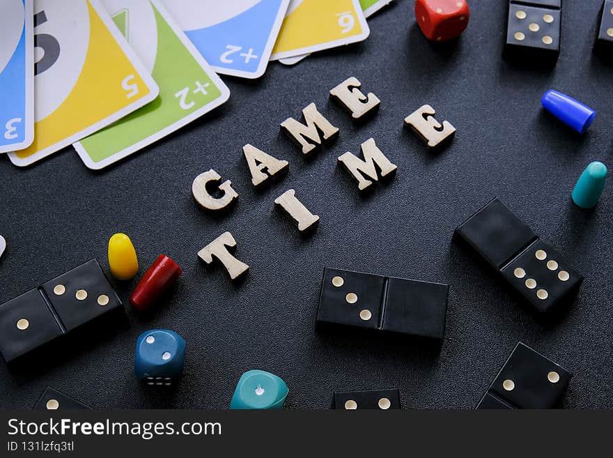 Kiev Ukraine - 10.03.21 Text GAME TIME spelled out in wooden letter. Surrounded by dice, dominoes uno playing cards on
