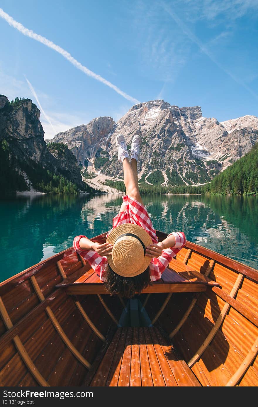 woman sitting in big brown boat at lago di braies lake in Italy. summer vacation