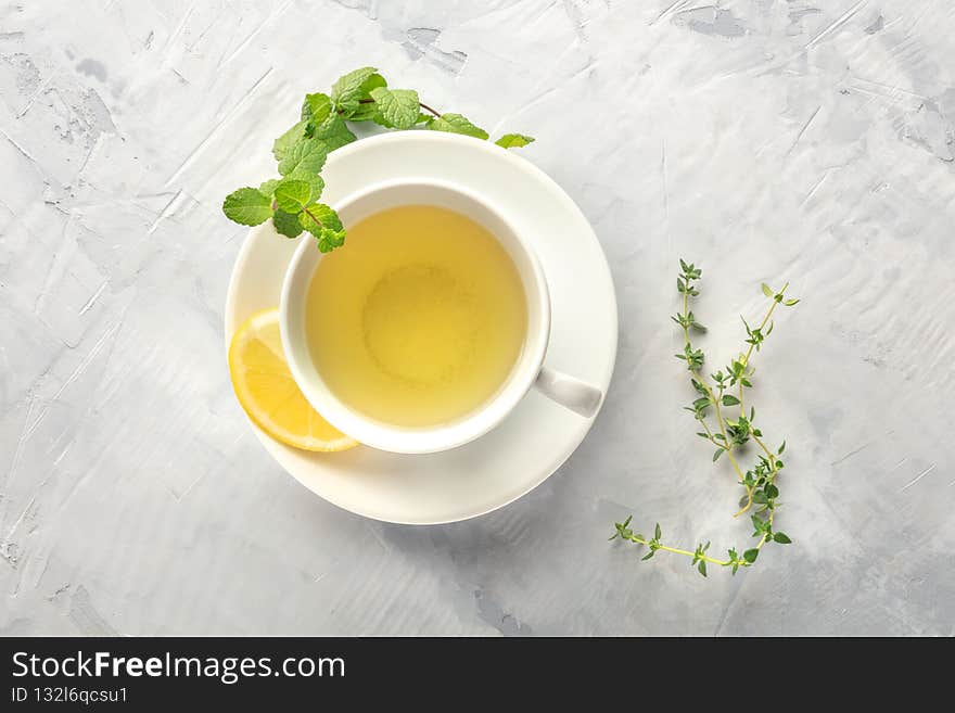 A cup of green tea with lemon, shot from above with mint, thyme, and copy space