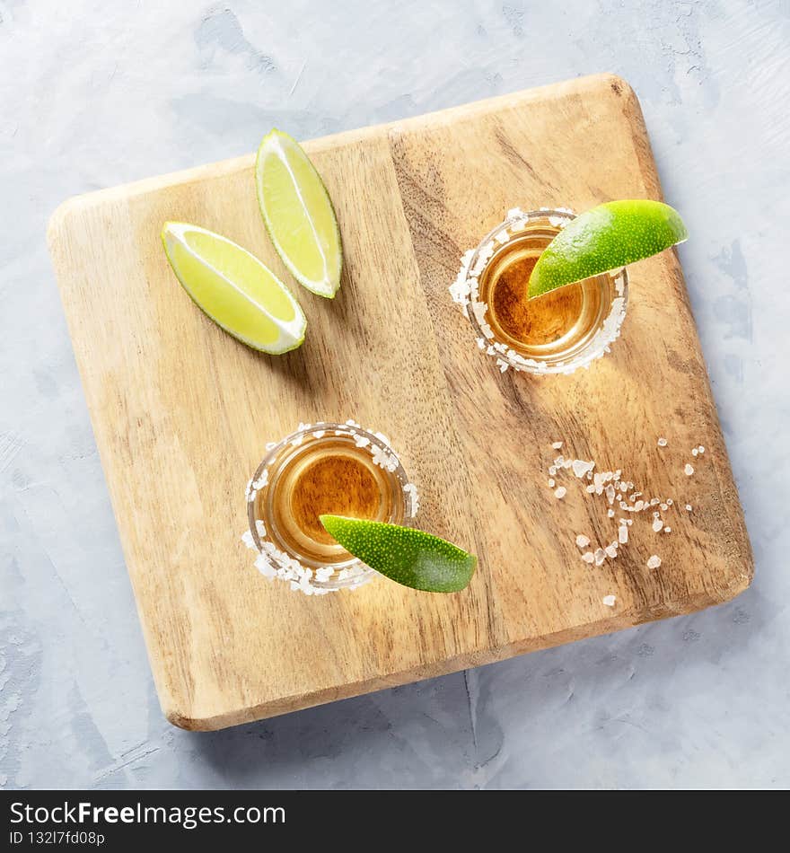 Golden tequila shots with lime slices and salt rims, overhead square shot