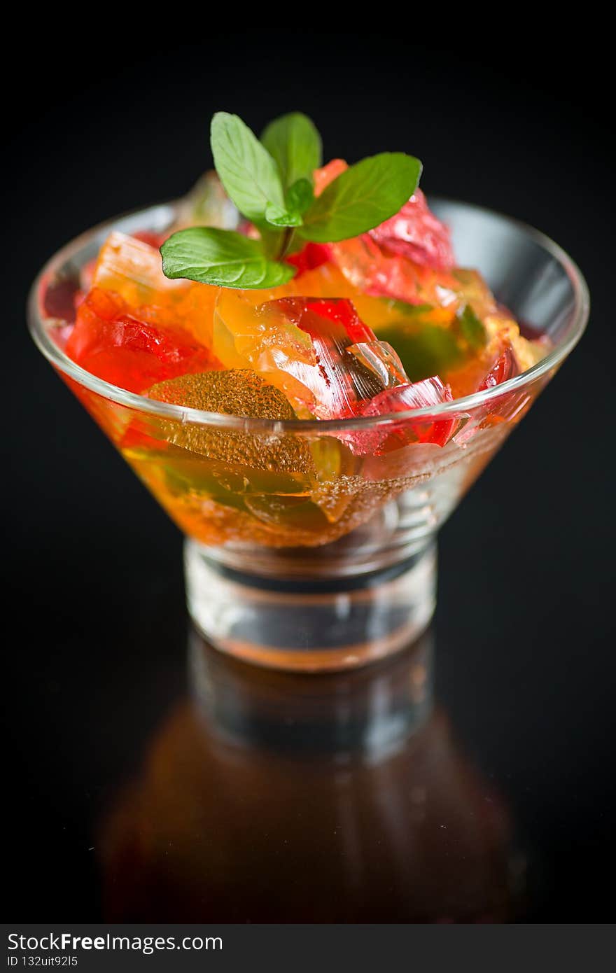 colored sweet fruit jelly in glass glass isolated on black background. colored sweet fruit jelly in glass glass isolated on black background