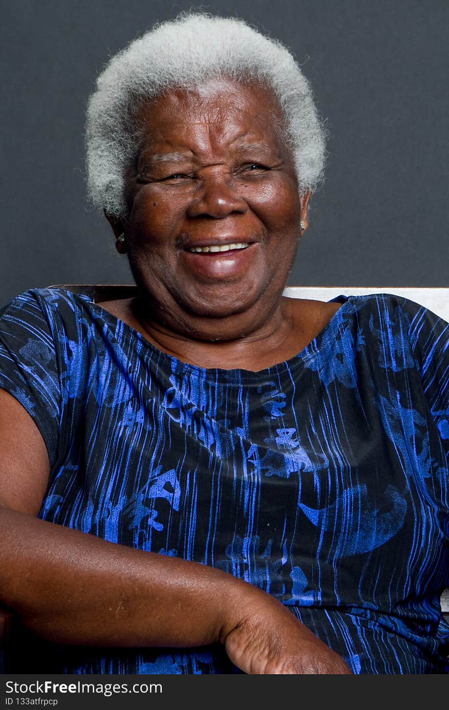 Elderly black woman with gray hair  laughing sitting dignified and proud on black background. Elderly black woman with gray hair  laughing sitting dignified and proud on black background