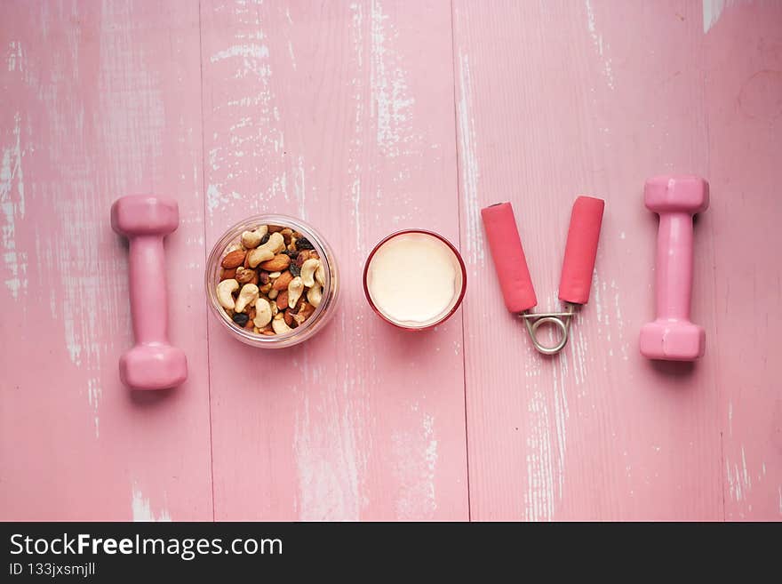 mixed nut in a bowl, milk and dumbbell on table .
