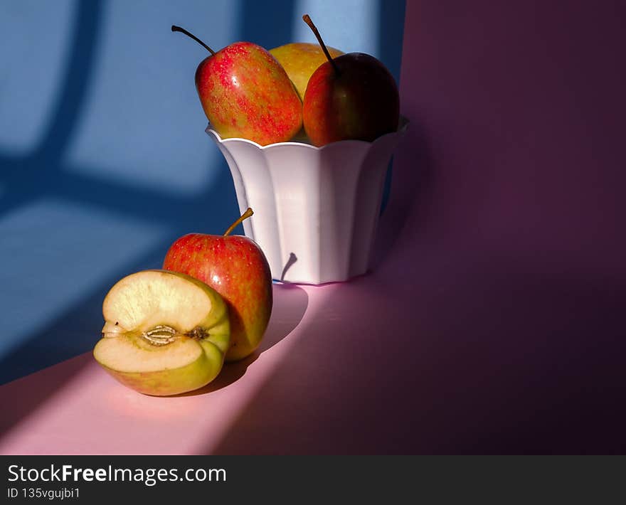 Photo of an apple in a container on a pink and blue background