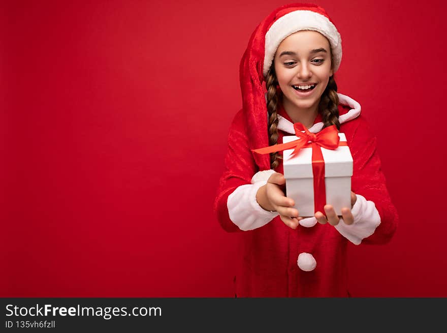 Shot of beautiful happy smiling brunette girl isolated over red background wall wearing new year santa claus outfit