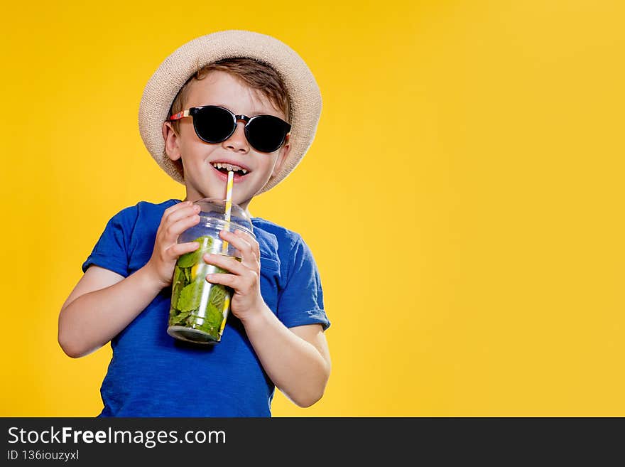 Cute boy Drink Mojito cocktail From Plastic Cup Over Yellow Studio Background
