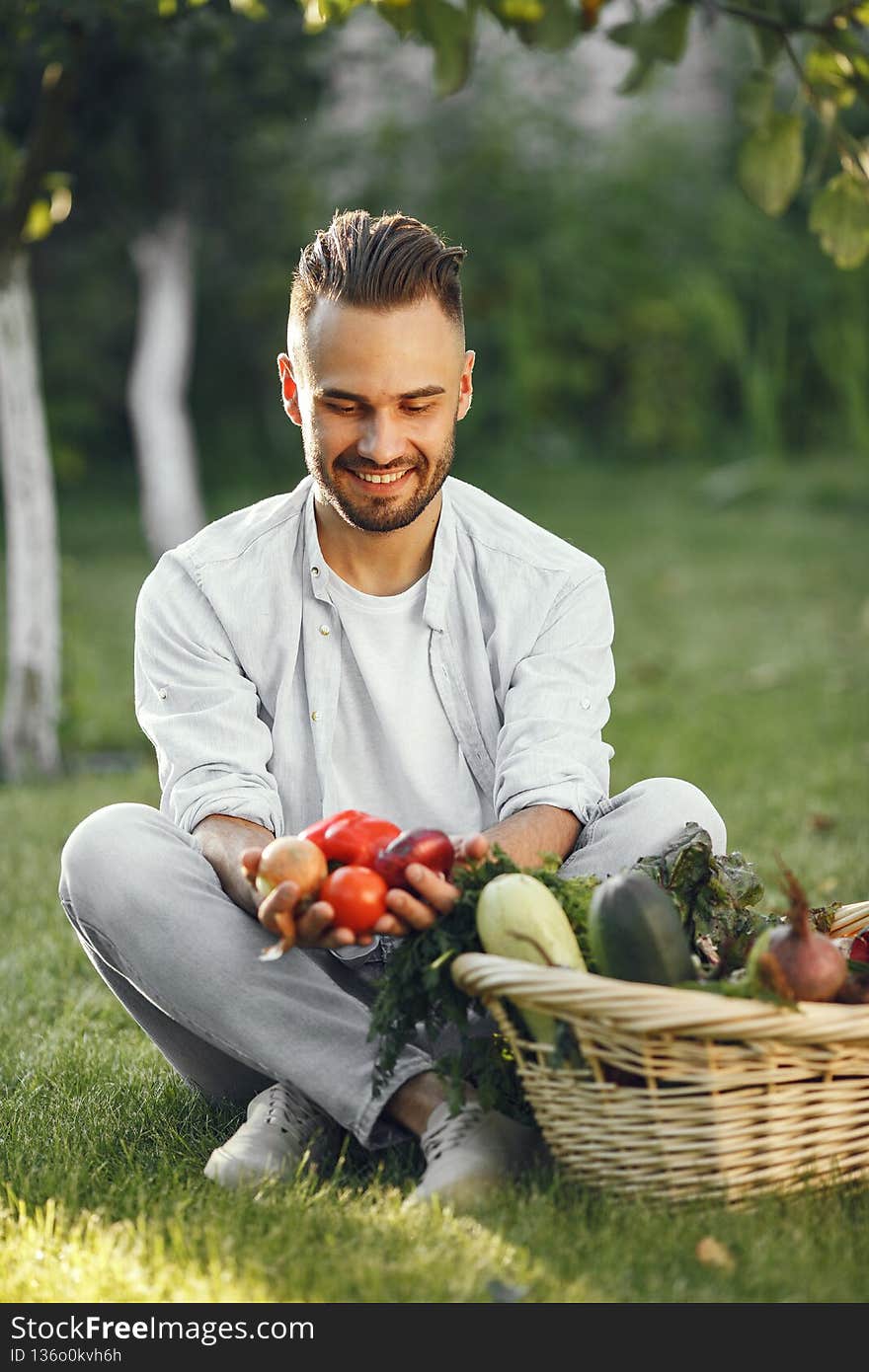Cheerful farmer with organic vegetables in garden. Mixed organic vegetable in wicker basket. Cheerful farmer with organic vegetables in garden. Mixed organic vegetable in wicker basket.