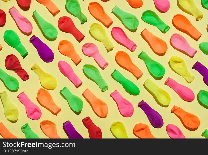 Deflacted balloons on yellow background, sunlight. Party background