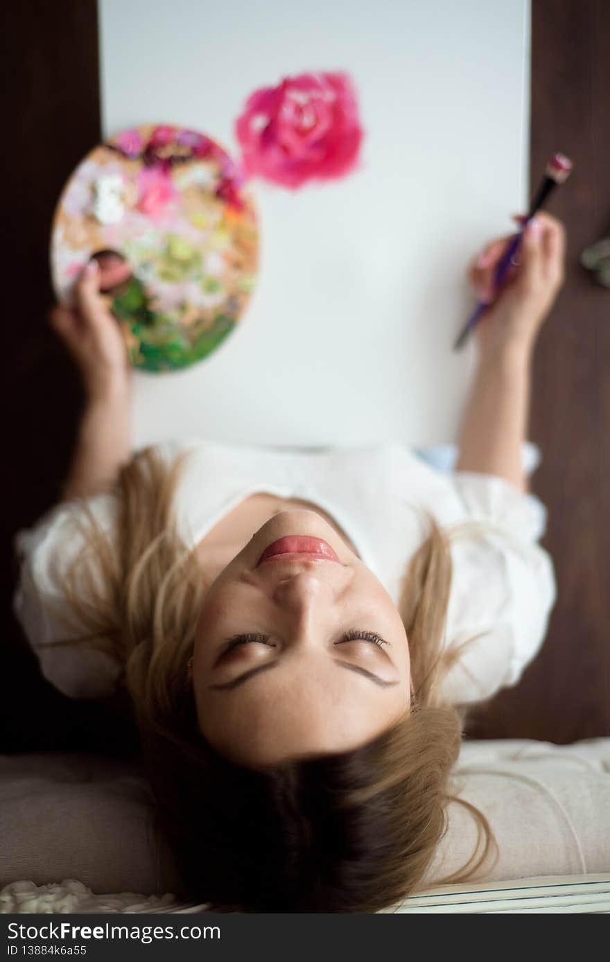 Beautiful woman artist drawing her picture on canvas with oil colors at home