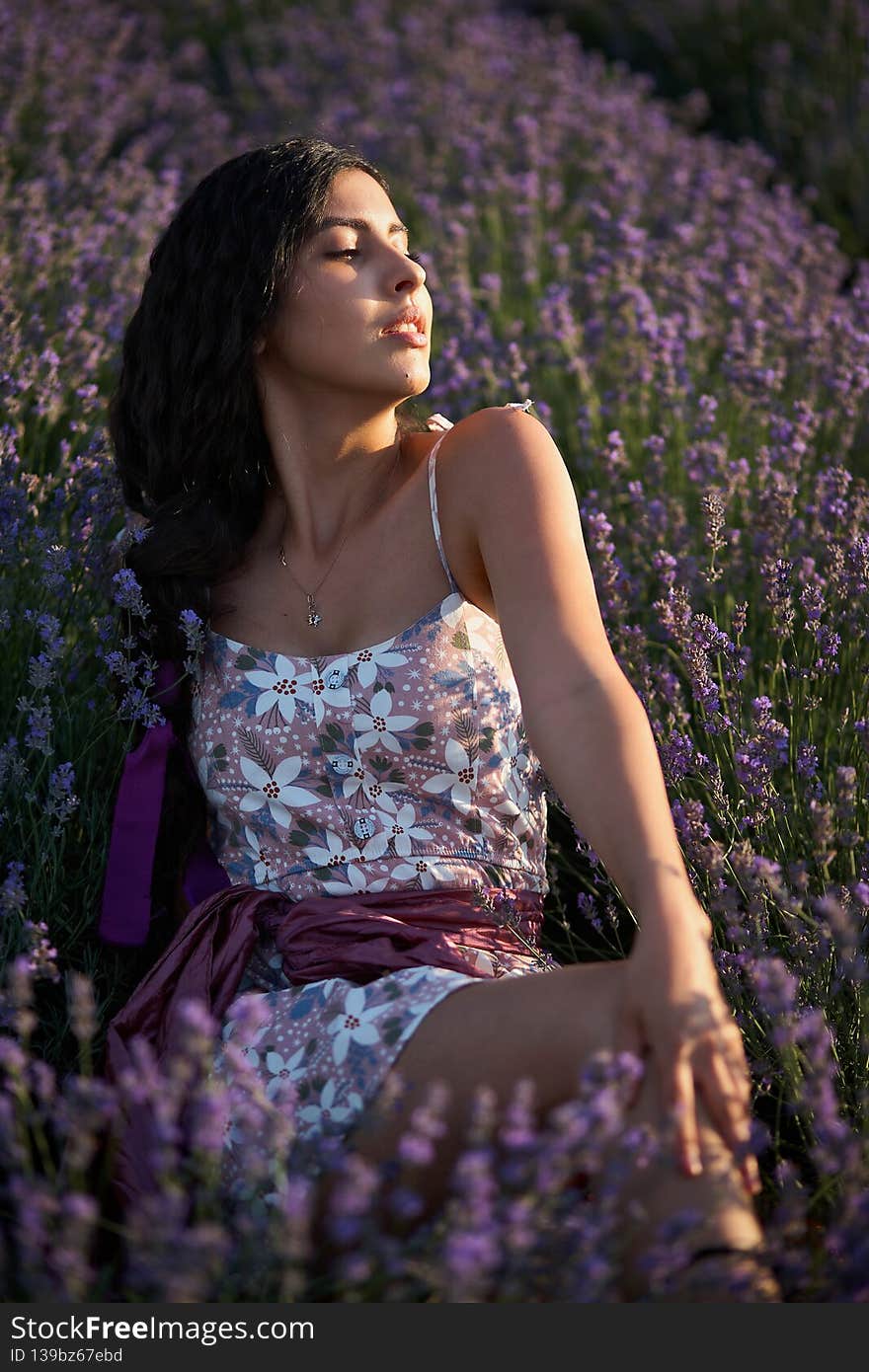 Portrait of lovely brunette girl in lavender field. Summer lavender model posing in front of the camera