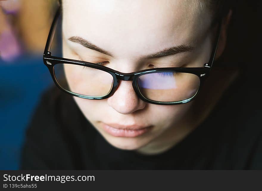 Charming young girl with glasses for working at the computer works online on the Internet, reads, writes close-up. Eye protection. Medical student. The teacher. A positive person. Selective Focus.