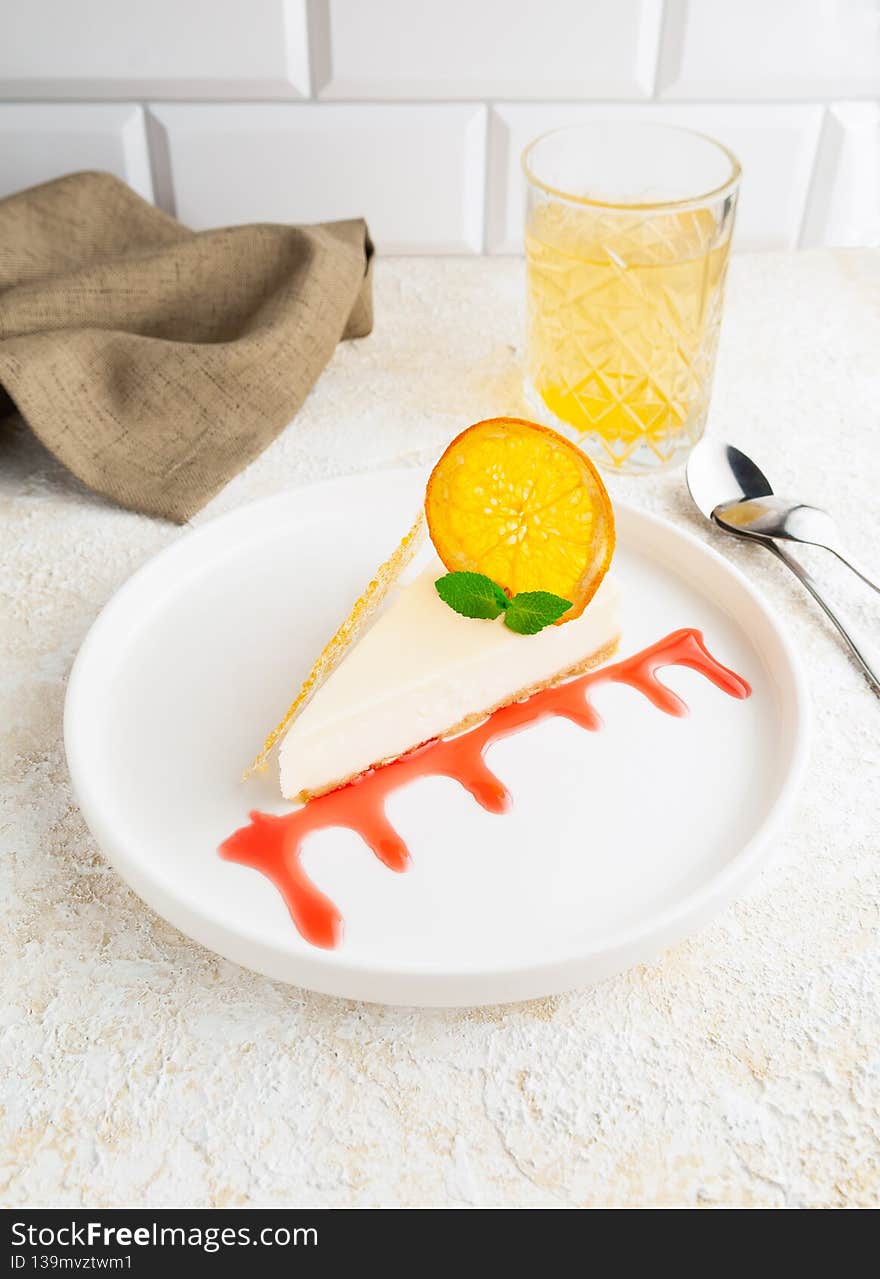 New York cheesecake with strawberry topping. Garnished with caramel and dried orange. On a flat white plate. Light background. View from above.