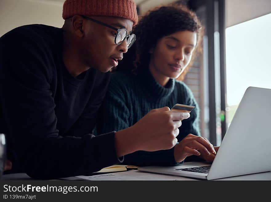 Close up of mixed race couple using laptop for online shopping. Happy, young African American couple using credit card to pay for online shopping. High quality photo. Close up of mixed race couple using laptop for online shopping. Happy, young African American couple using credit card to pay for online shopping. High quality photo