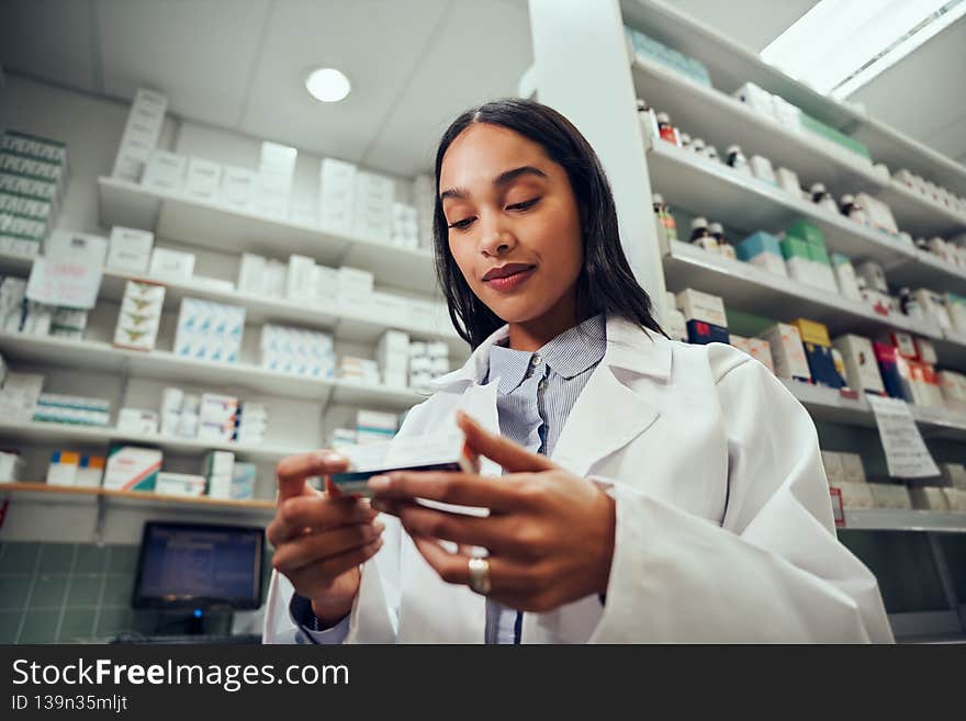 Low angle view of woman pharmacist reading medicine name in chemist. Low angle view of woman pharmacist reading medicine name in chemist